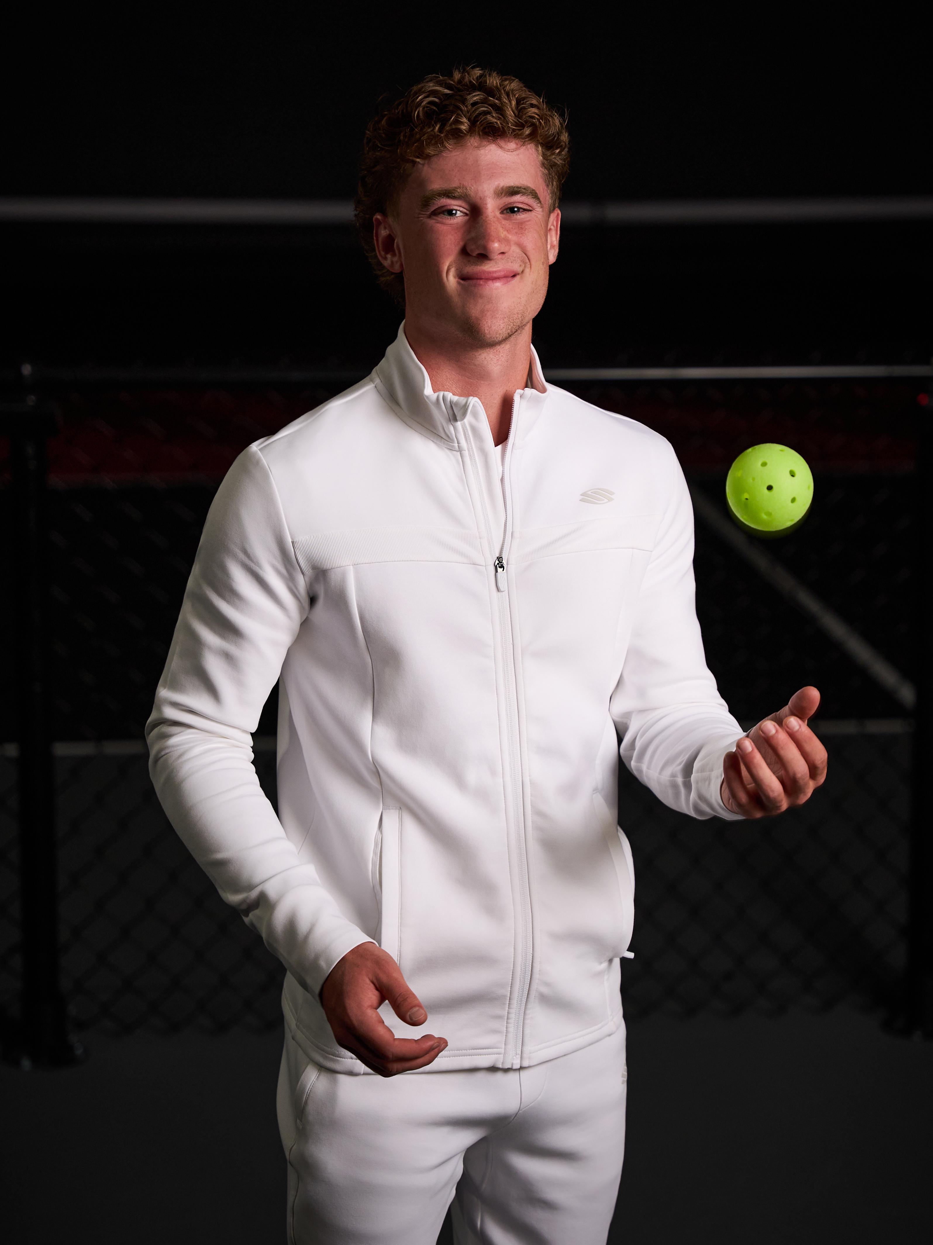 Model wearing a white men's Pro Line Full Zip Jacket, holding a pickleball.