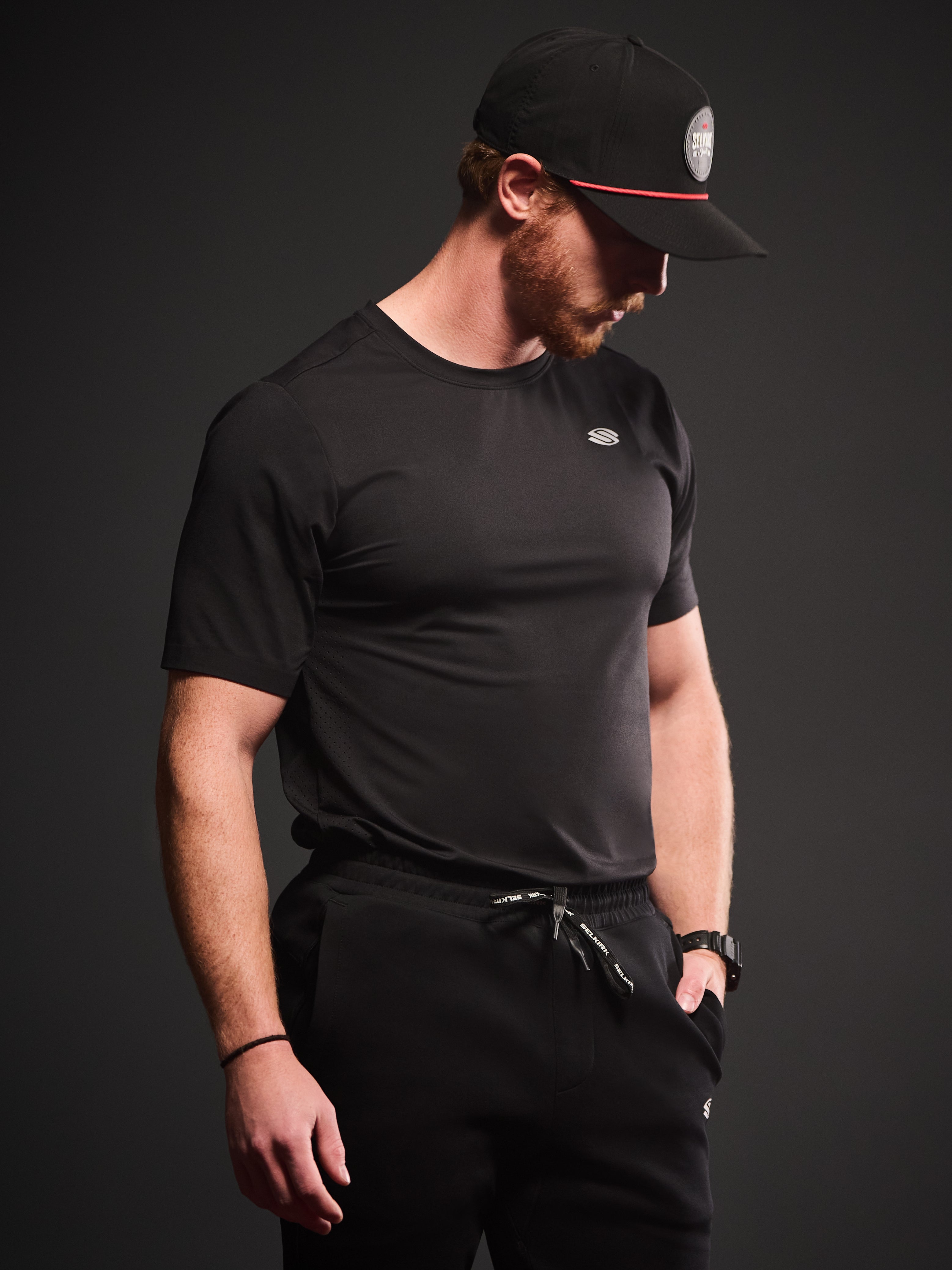 Model wearing a black short sleeve athletic shirt and black pants, showcasing the fit and style.
