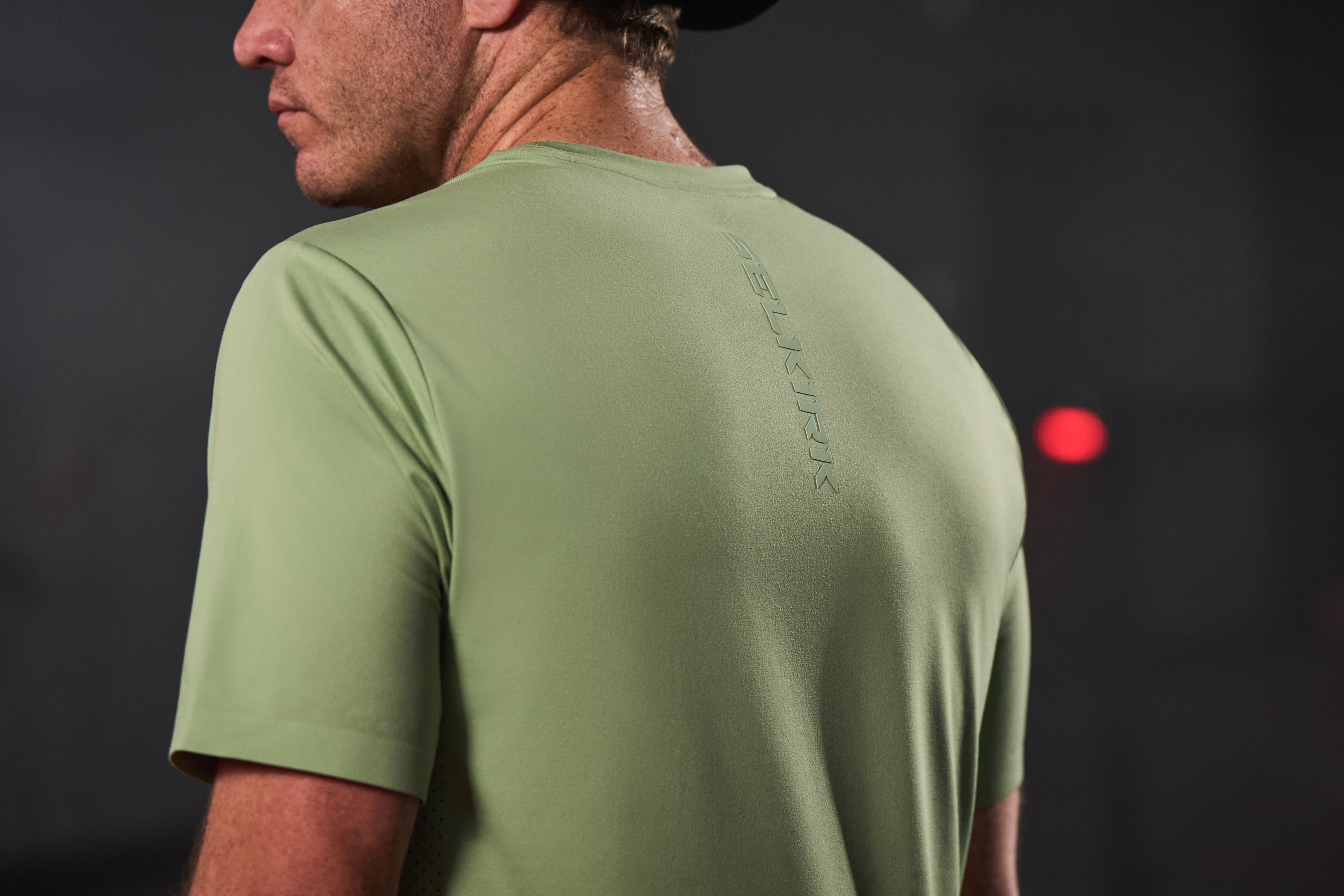 Man wearing a light green short-sleeve athletic shirt with logo on the back
