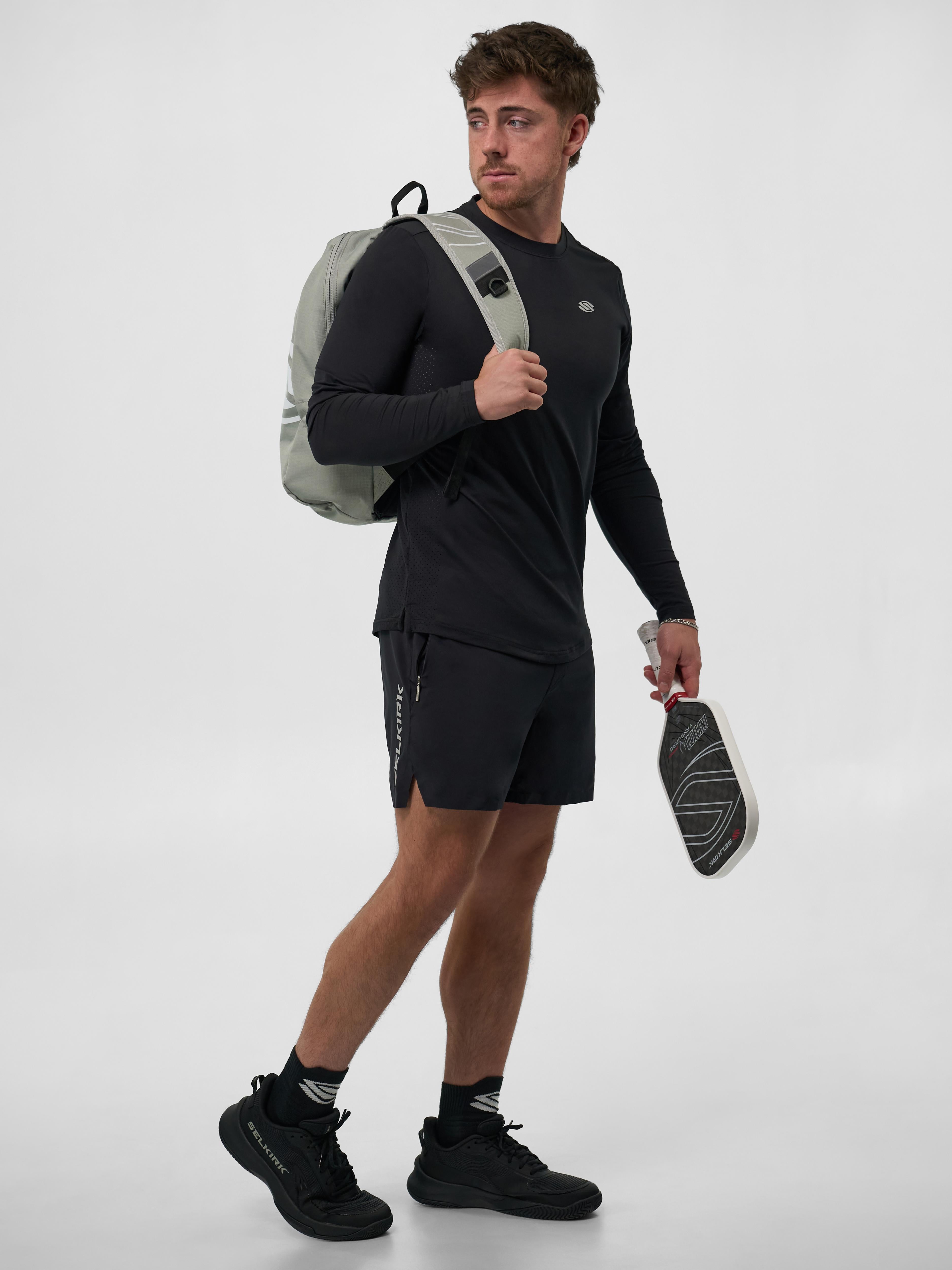 Model wearing the Men's Pro Line Athletic Long Sleeve Shirt in black, holding a pickleball paddle and wearing shorts.