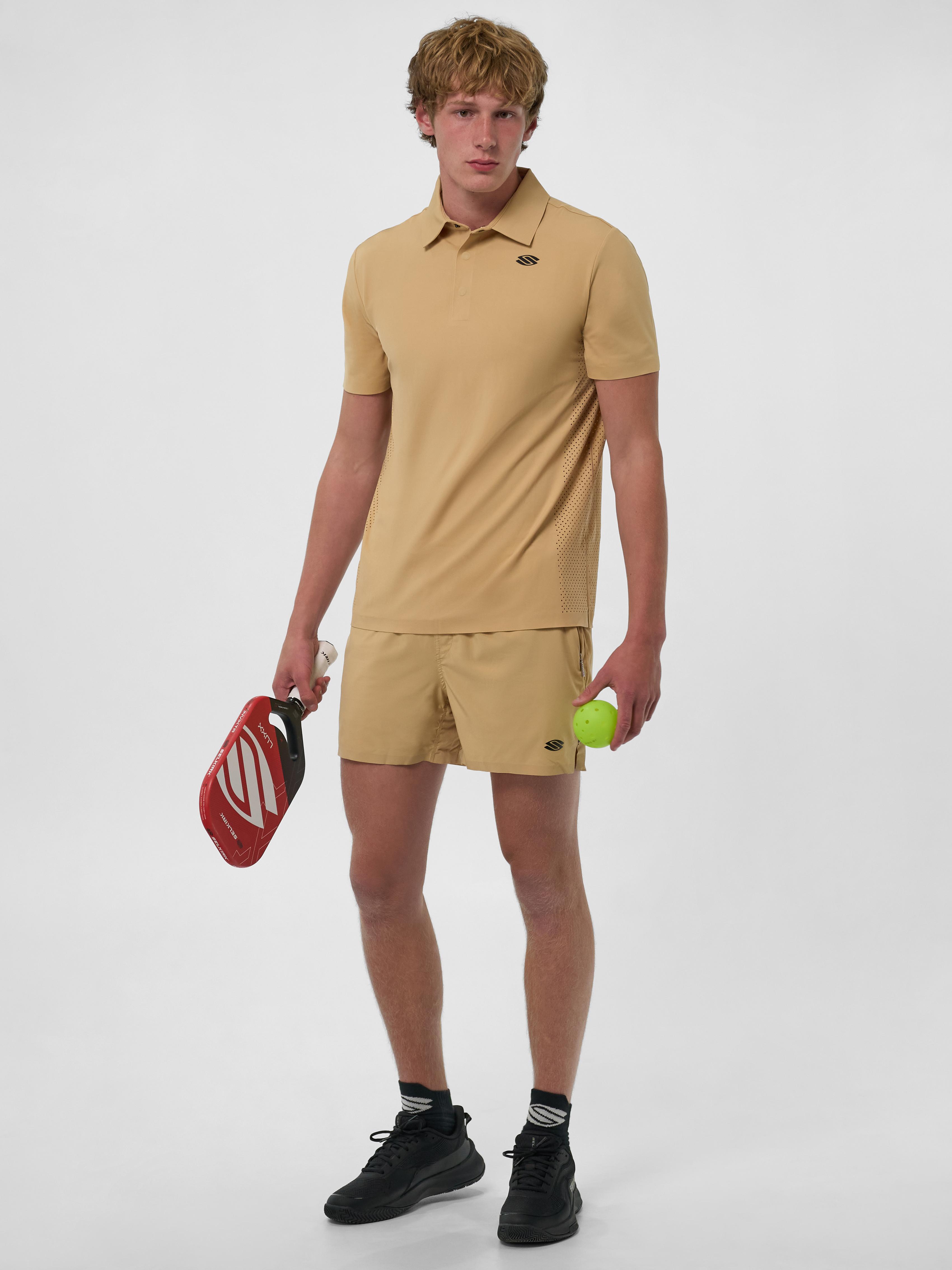 Model wearing a men's performance polo in beige, holding a pickleball paddle and ball.