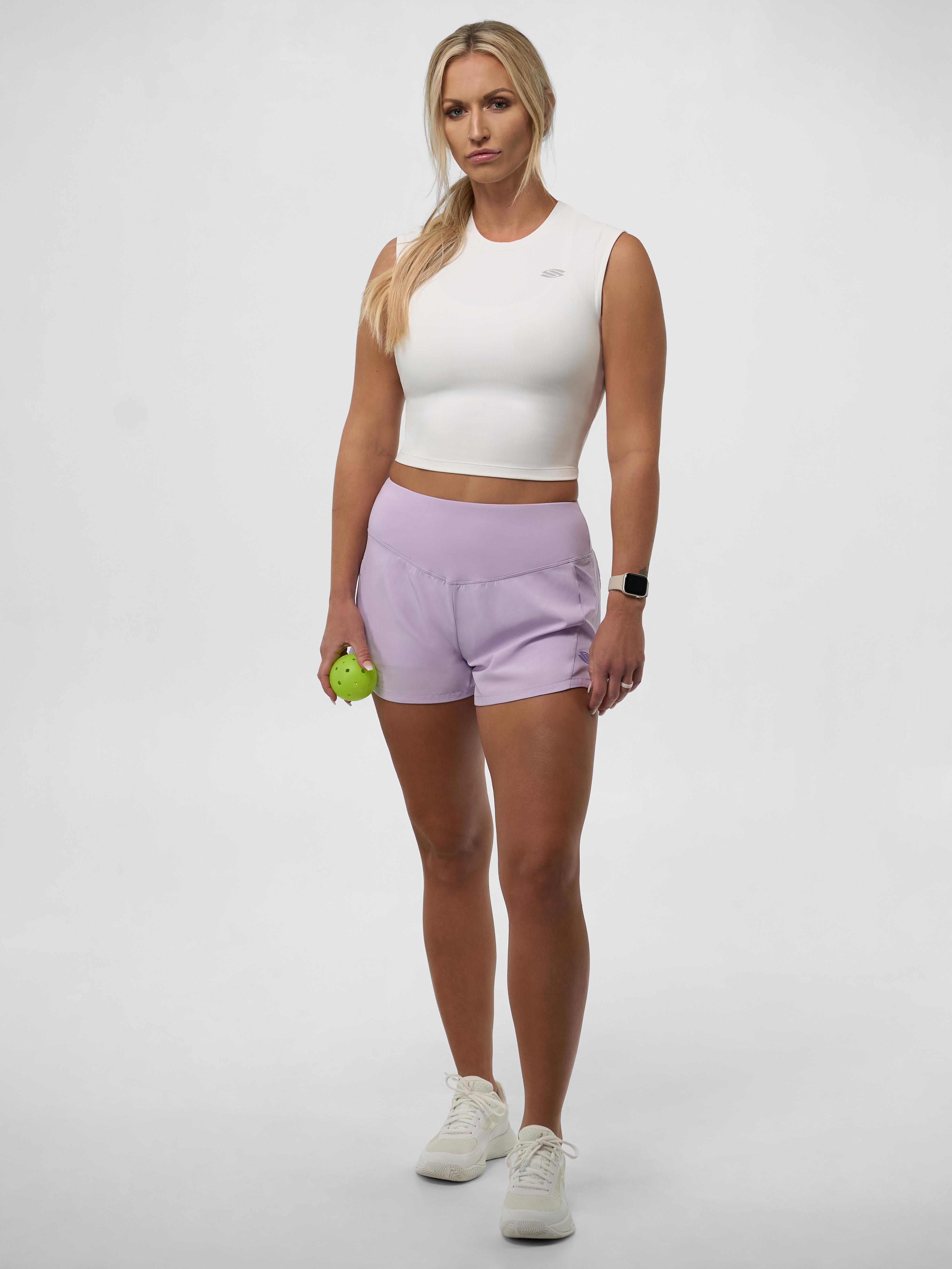 Model wearing Women's Pro Line Cap Sleeve Fitted Tee with purple shorts, holding a green ball.