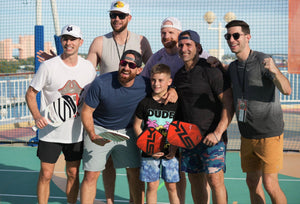 Group of people, including a child, holding pickleball paddles at a pickleball event.
