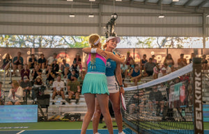 Two female pickleball players embracing at the net after a match.
