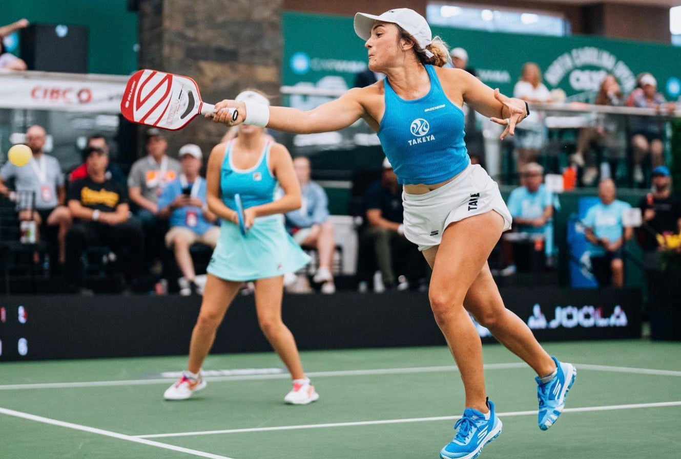 Catherine Parenteau hitting a pickleball with Anna Leigh Waters in the background during a match at the PPA North Carolina Open.