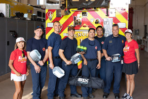 Firefighters holding pickleball paddles and balls in front of a fire truck