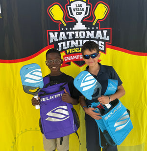 Two young players holding Selkirk paddles and backpacks at the National Juniors Pickleball Championships