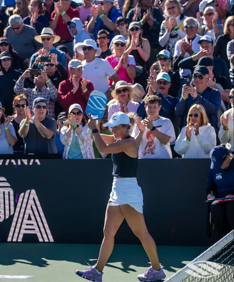 Catherine Parenteau celebrating after winning her 60th match, with a cheering crowd in the background.