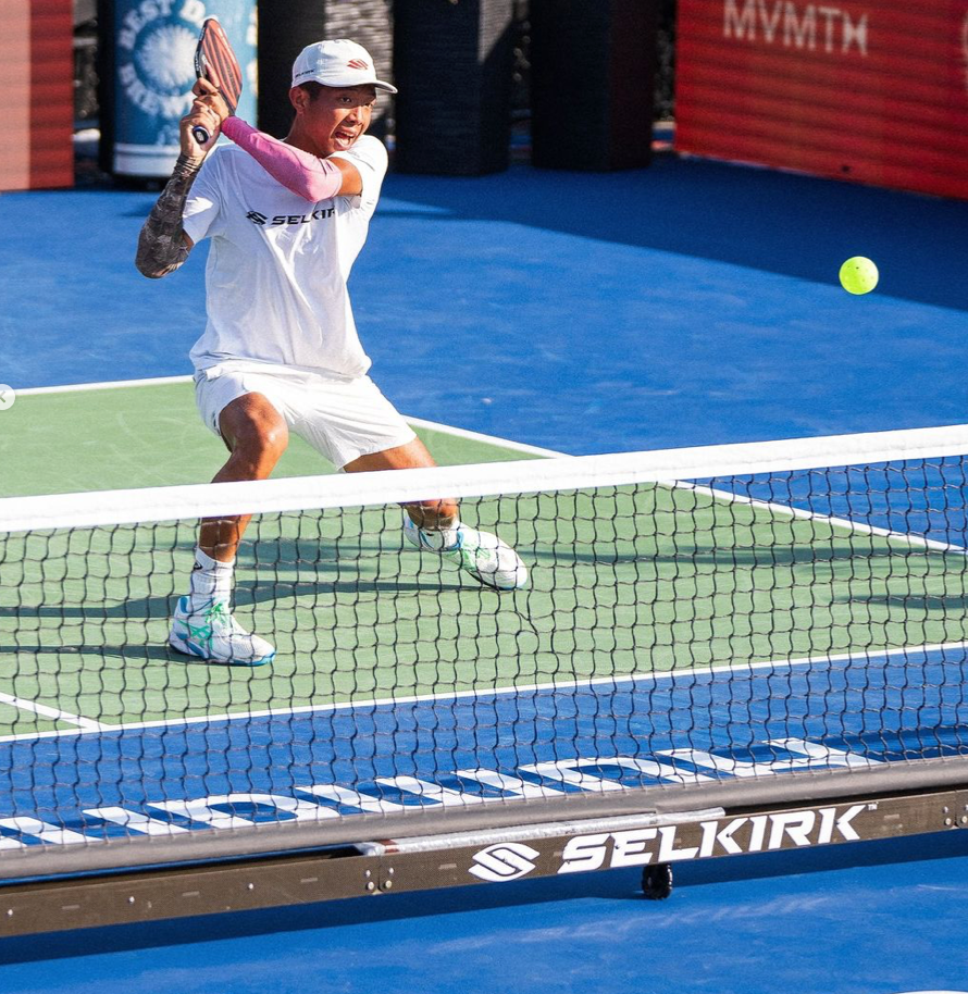 Quang Duong hitting a pickleball during a match on the court