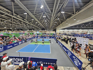 Indoor pickleball tournament with players competing before a large seated crowd