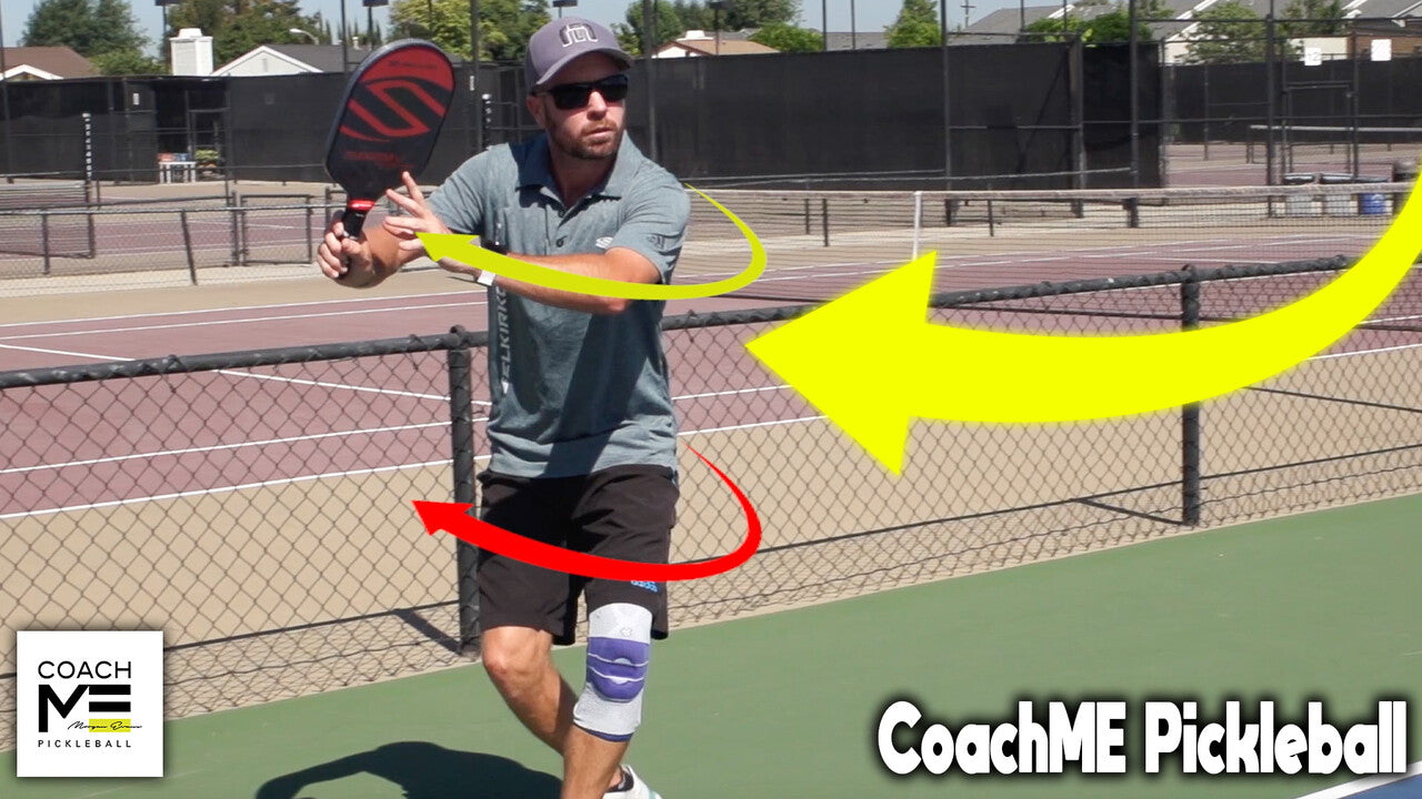 Man preparing a backhand on an outdoor pickleball court with yellow motion arrows and CoachME Pickleball logo