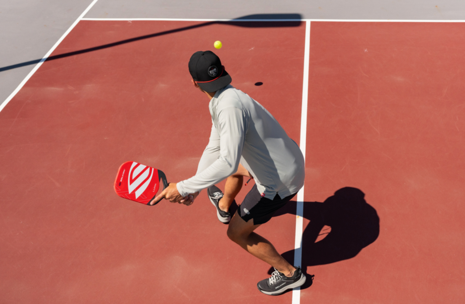 An image shows the back of a man as he executes a backhand drive with a LUXX Control Air with Infinigrit. 