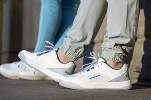 A close-up image shoes a man and woman wearing the Legacy shoes as they sit on a bench. 
