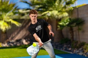 A man prepares to hit a lob shot with his Selkirk pickleball paddle. 