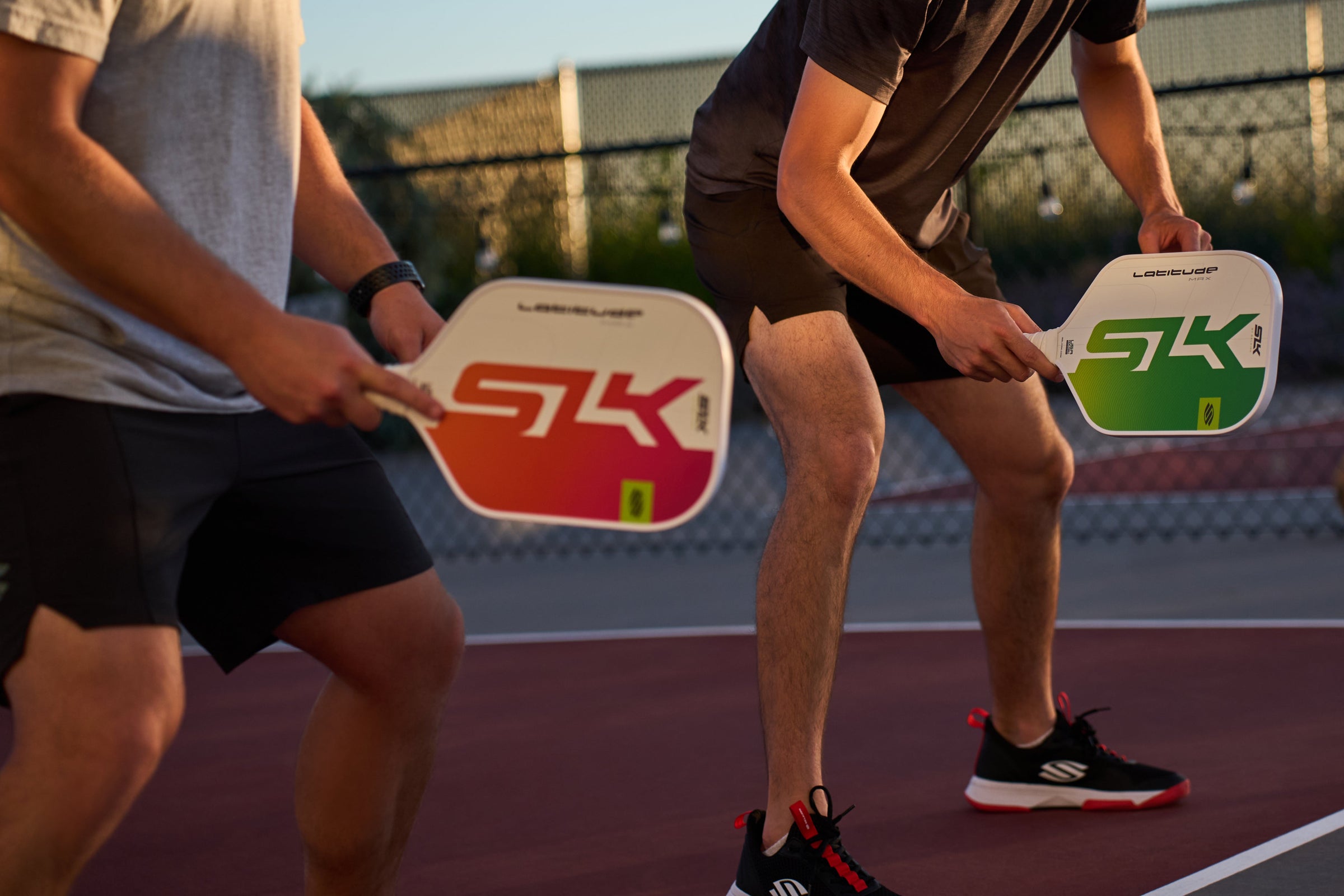 Two pickleball players practicing with paddles on a court.