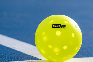 A Selkirk S2 Pro pickleball sits on the baseline of a pickleball court. 
