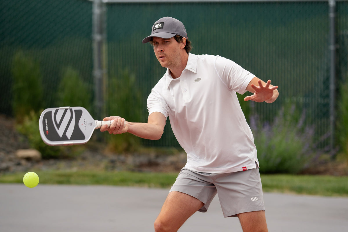 A man returns a serve using a Selkirk Omni pickleball paddle. 
