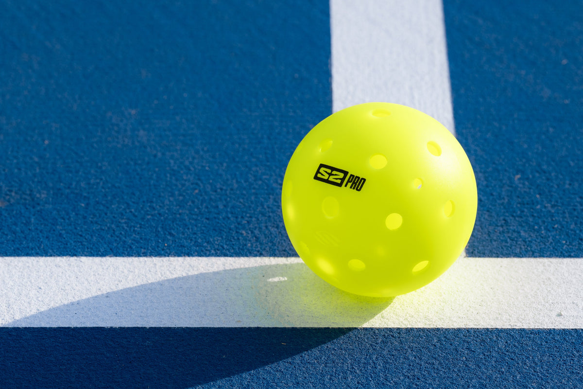 A Selkirk S2 Pro pickleball sits on the baseline of a pickleball court. 