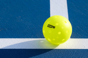 A Selkirk S2 Pro pickleball sits on the baseline of a pickleball court. 