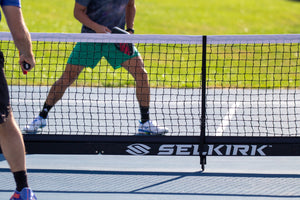A close-up image shoes a ball just crossing a Selkirk net. 