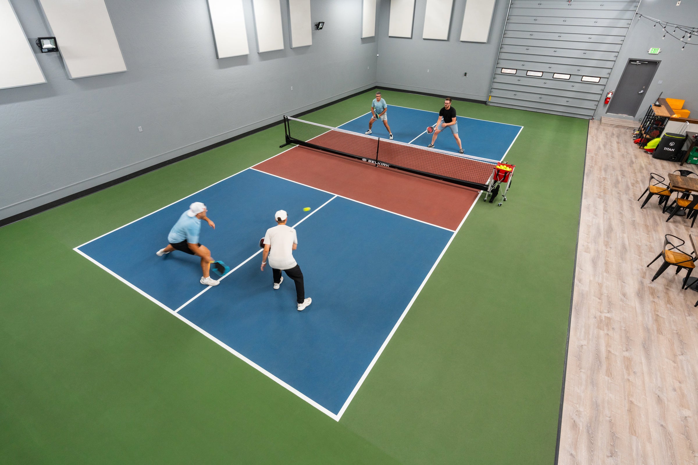 An overhead image shows four people playing pickleball on an indoor pickleball court. 