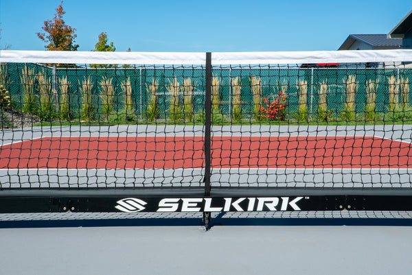 Selkirk Semi-Permanent Pro Pickleball Net with a black frame and netting on a court