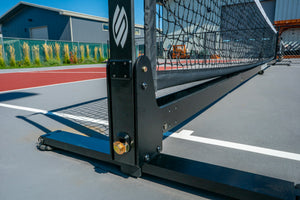 Portable pickleball net post and wheeled base close-up on outdoor court
