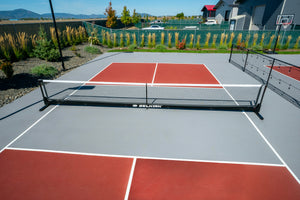 Selkirk Semi-Permanent Pro Pickleball Net set up on a court with red playing surface.