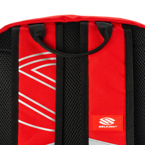 Red backpack shoulder straps with black mesh padding and a small patch reading SELKIRK.