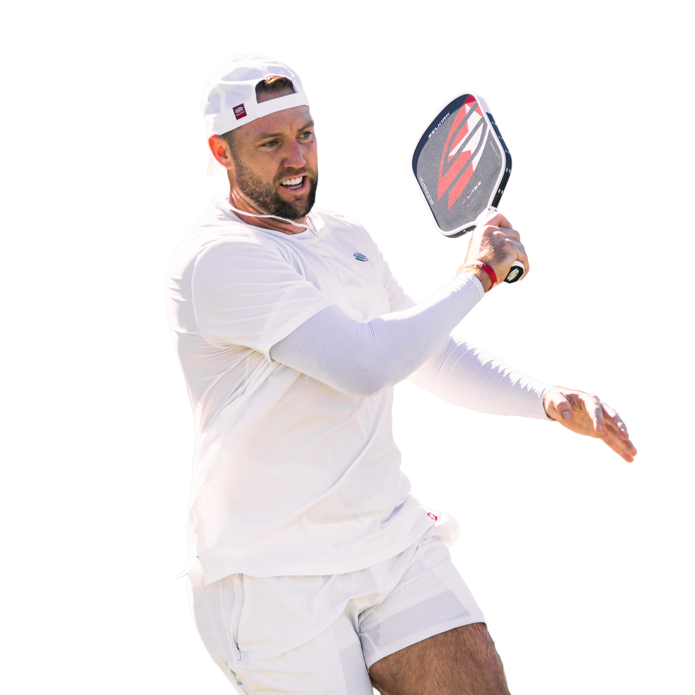 Professional pickleball player swinging a Selkirk paddle while wearing white athletic clothing