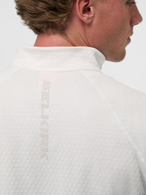 Person wearing white textured pullover with vertical SELKIRK logo on the upper back