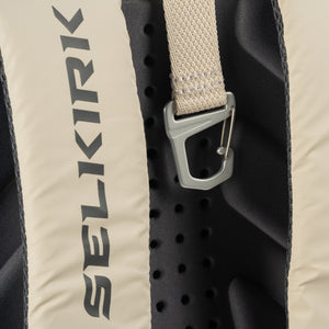 Vertical SELKIRK logo on beige backpack back panel, perforated black foam and metal strap clip.