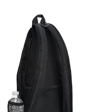Black sling backpack with padded shoulder strap, mesh side pocket holding a water bottle, and zippered main compartment