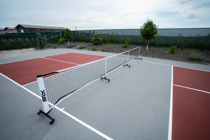 SLK Prime Portable Pickleball Net with wheels set up on a court