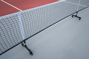 Portable pickleball net with wheels on a court surface