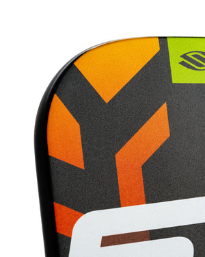Close-up of snowboard tip with orange geometric arrows and white partial logo on black textured surface