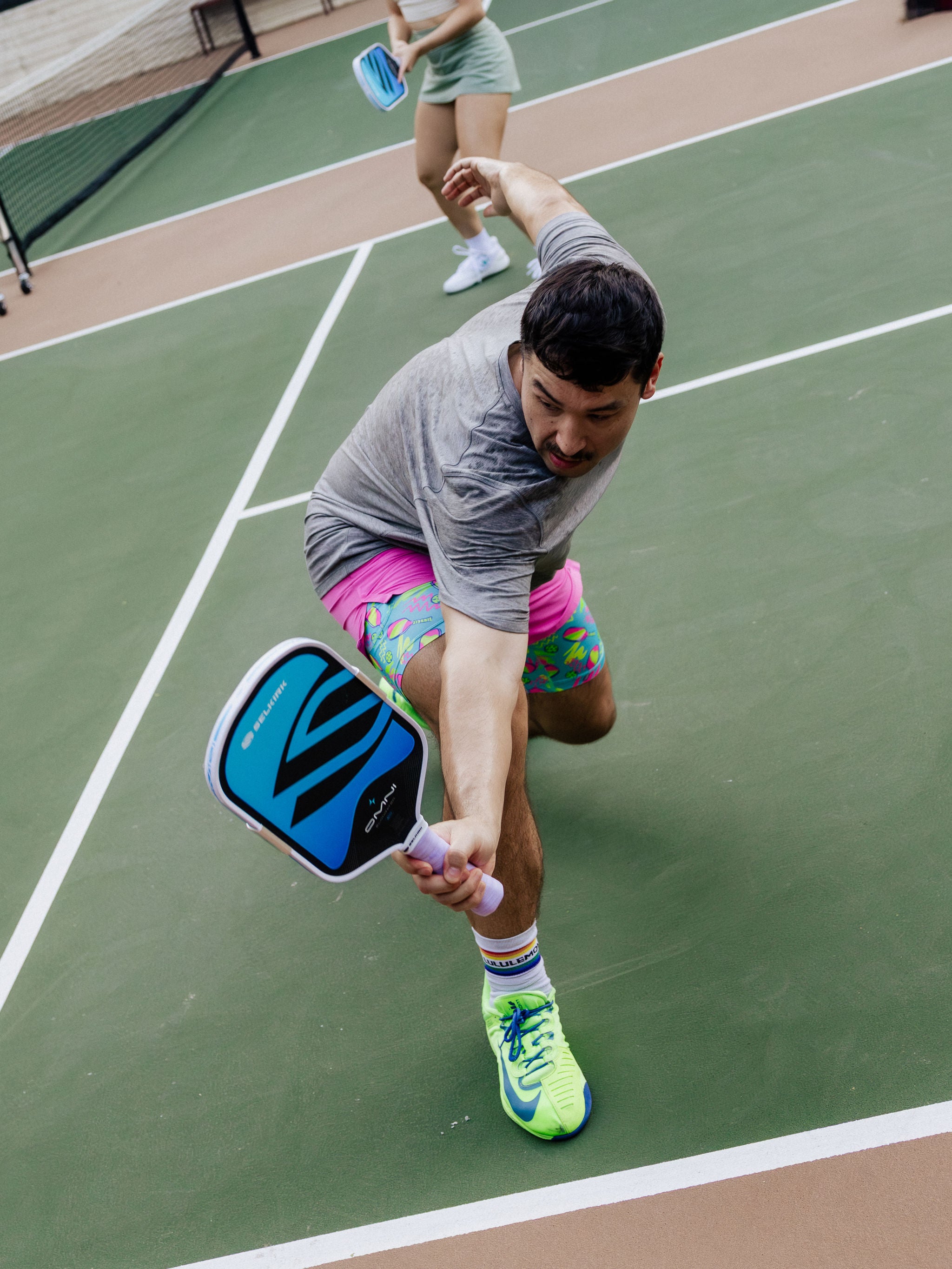 A man reaches for a backhand shot with his Selkirk OMNI pickleball paddle on an outdoor court. 