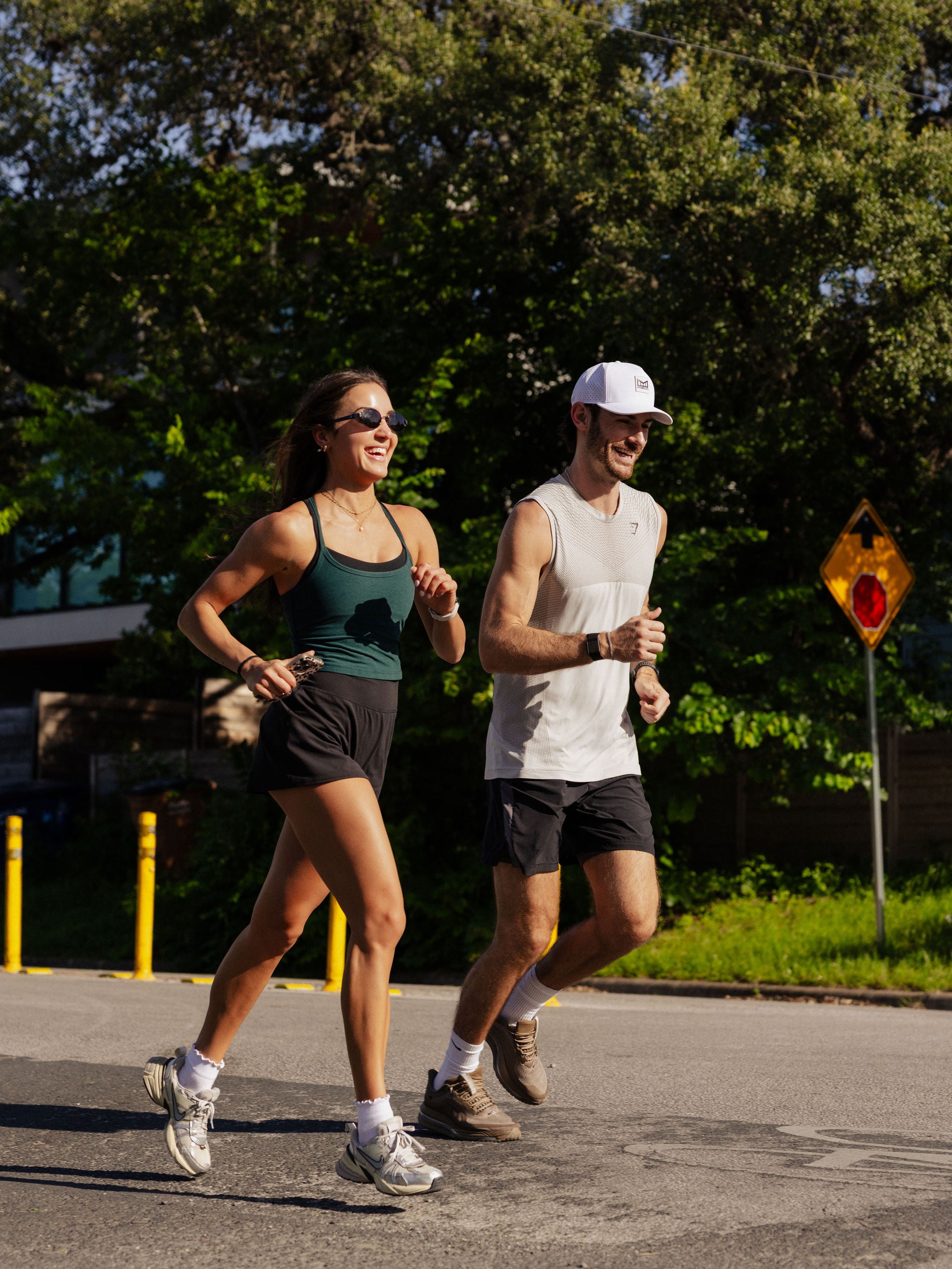 A man and a woman smile as they run side-by-side outside. 