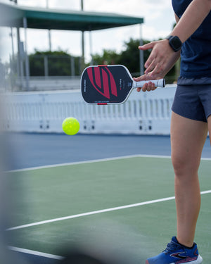 Player hitting a pickleball with the black Boomstik paddle