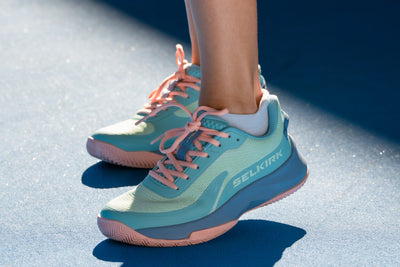 A woman wearing light blue Courtstrike 2.0 shoes on the court