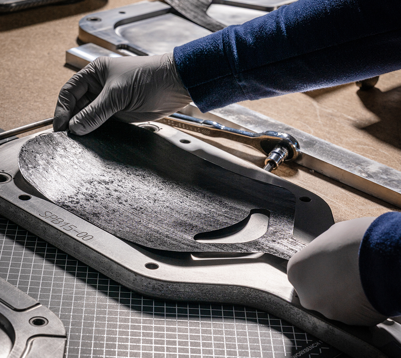 Close-up of gloved hands crafting a Selkirk Sport pickleball paddle face using advanced composite materials and a custom mold for high-performance paddle engineering.