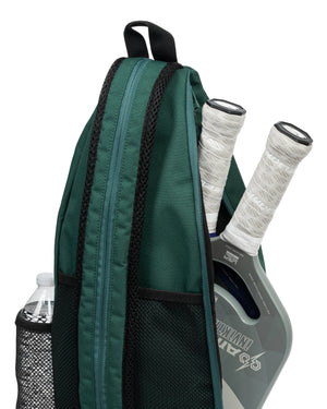 Green sling backpack with two paddles with white grips and a water bottle in a mesh side pocket