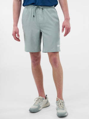 Man in light gray knee-length athletic shorts with drawstring and small left-leg logo, paired with gray running shoes.