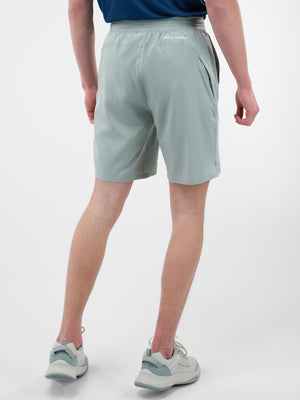 Back view of person wearing pale green Selkirk athletic shorts and matching sneakers.