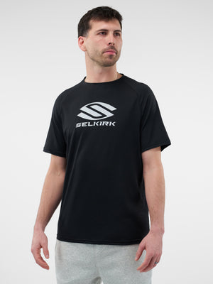 Adult man standing, wearing black T-shirt with large 'SELKIRK' logo and gray sweatpants, looking to the right.