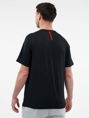 Man seen from back wearing black short-sleeve athletic T-shirt with small vertical red logo at upper back