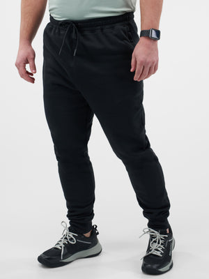 Lower-body view of a man wearing black jogger pants with drawstring and black athletic sneakers