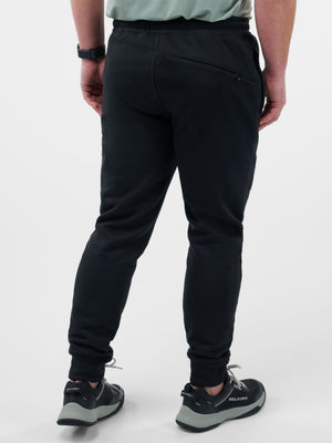 Rear view of person wearing black jogger pants and gray-black sneakers labeled BELKIRK.