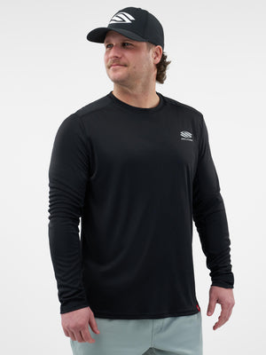 Adult man wearing a black long-sleeve athletic shirt and cap with SELKIRK logo on chest and cap