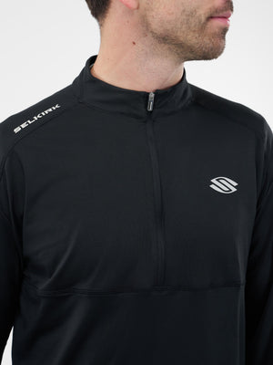 Man wearing black quarter-zip athletic top with SELKIRK text on shoulder and white brand logo on chest